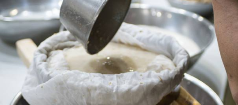 Pouring liquid through a cloth filter during makgeolli brewing